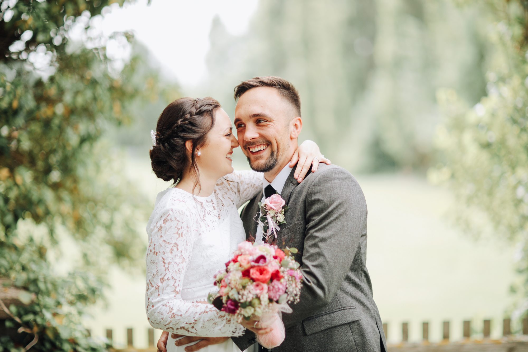 Lachendes Brautpaar bei einer Sommerhochzeit im Grünen
