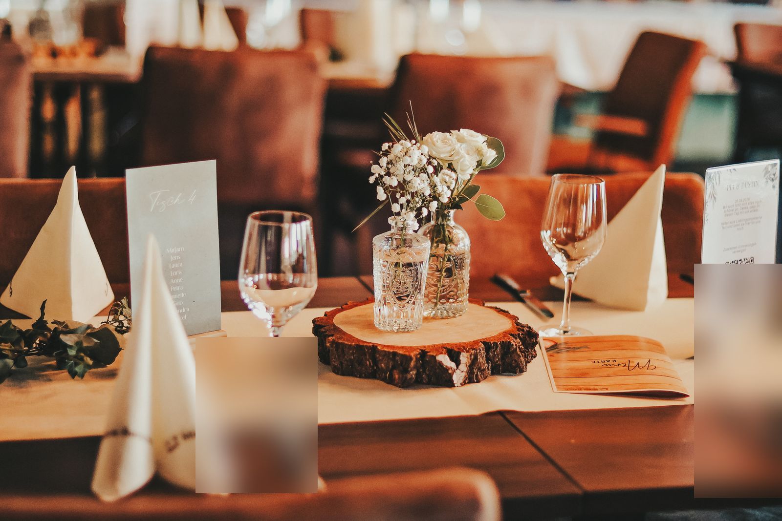 Gedeckter Hochzeitstisch mit Tischnummer, Blumendeko auf Holzscheibe und Menükarte