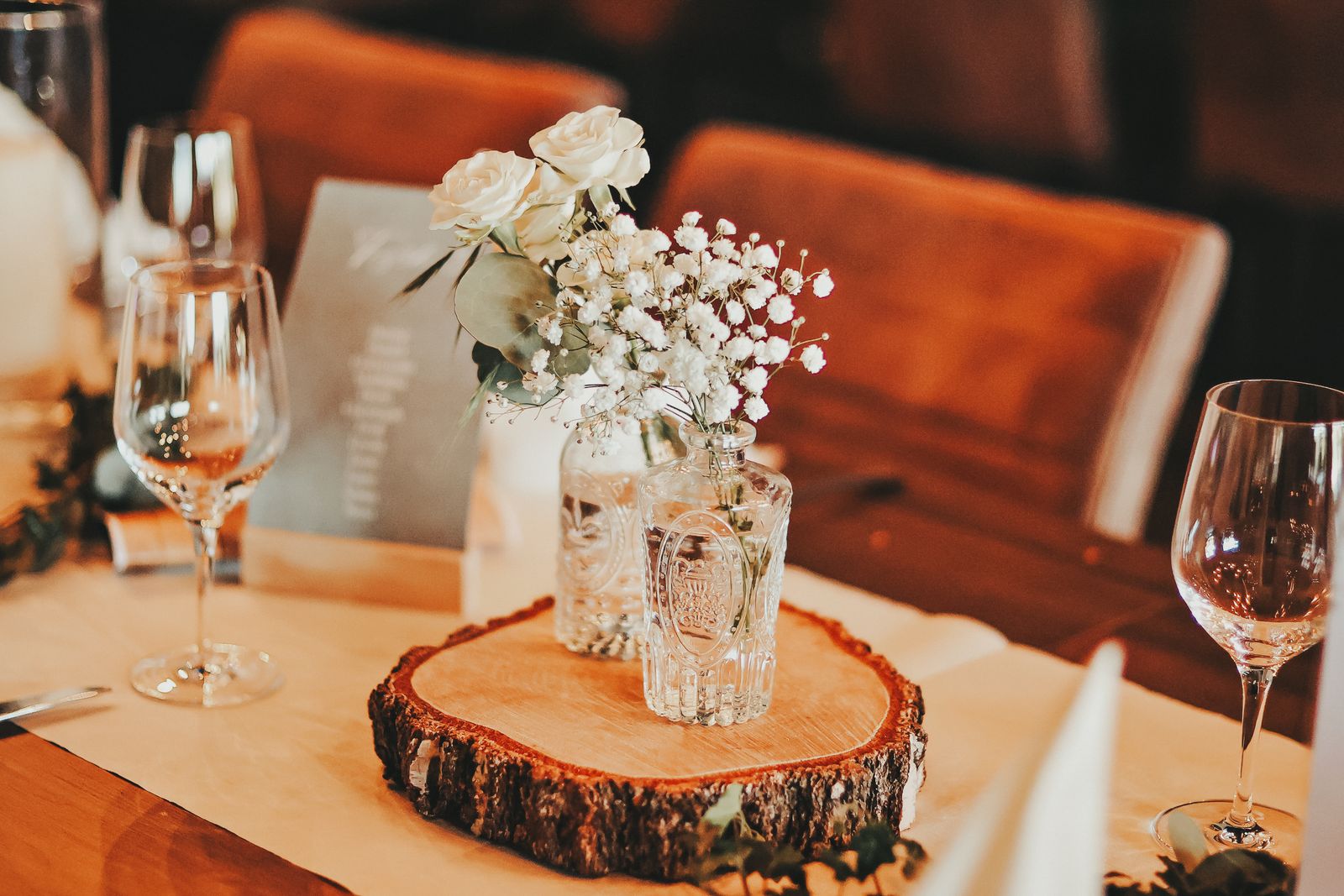 Rustikale Hochzeitsdeko: Baumscheibe mit kleinen Glasvasen und weißen Blumen