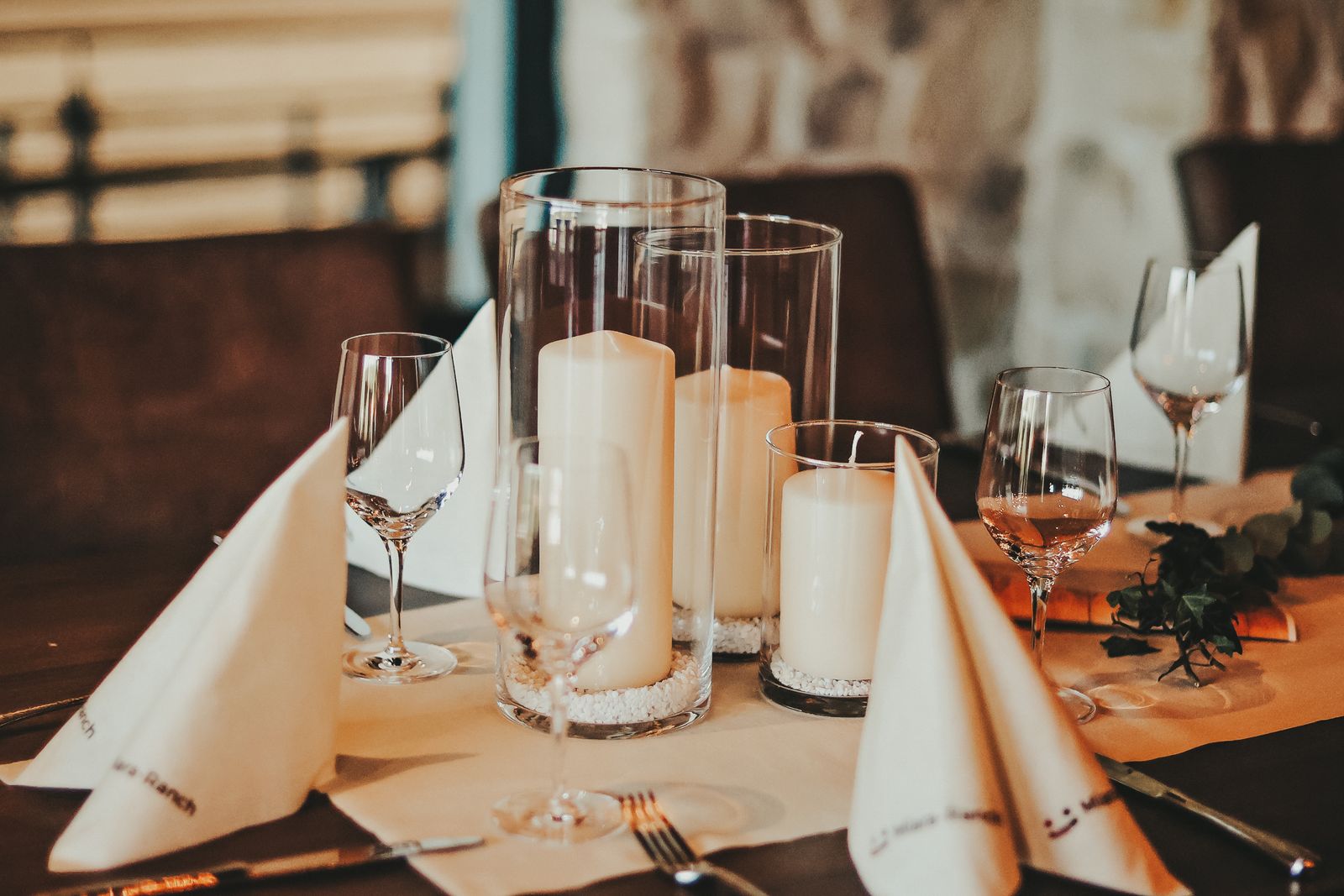 Kerzenensemble in Glaszylindern mit weißen Kieselsteinen als Hochzeitstischdeko