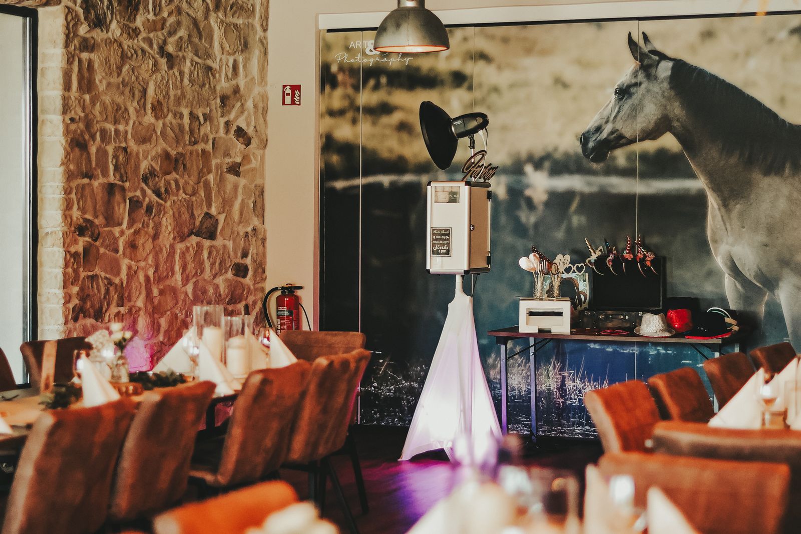 Fotobox mit Requisiten-Tisch im festlich dekorierten Hochzeitssaal